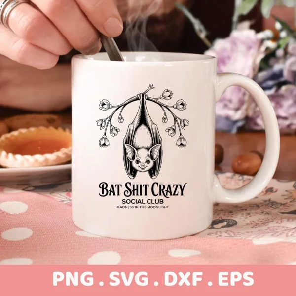 Close-up of a white mug featuring a Halloween bat Cricut design with the phrase "Bat Shit Crazy Social Club," intended for cutting or serigraphy applications.