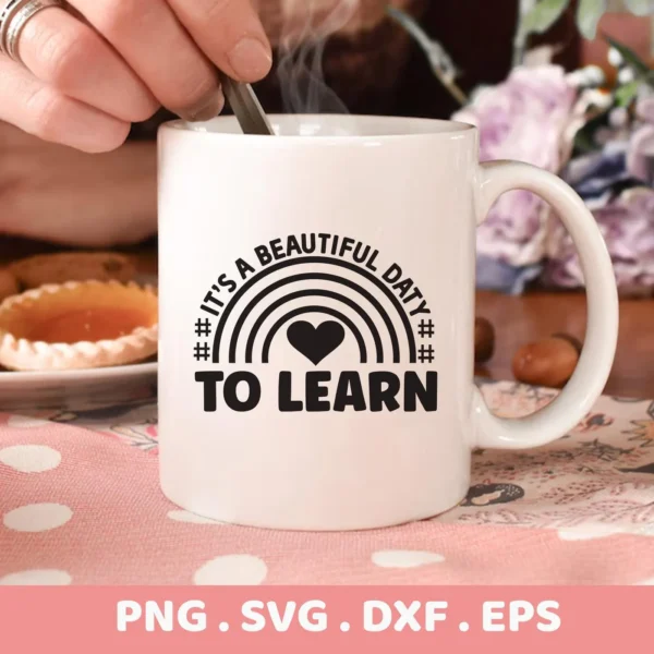 A white mug mockup featuring the "It's a Beautiful Day to Learn" SVG design with a rainbow and heart, available as a digital download bundle (SVG, PNG, DXF, EPS) for Cricut crafts.