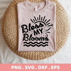 A folded light pink t-shirt with the text "Bless My Blooms" in black script font, displayed on a round woven mat, representing a Bless My Blooms SVG digital download bundle.