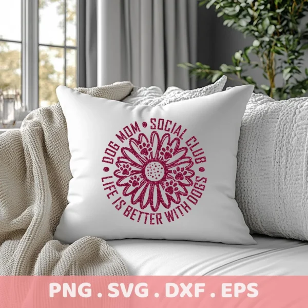 A white throw pillow on a couch displays a maroon-colored "Dog Mom Social Club" design featuring a flower with paw prints, and the phrase "Life is Better with Dogs," representing a digital download bundle (SVG, PNG).