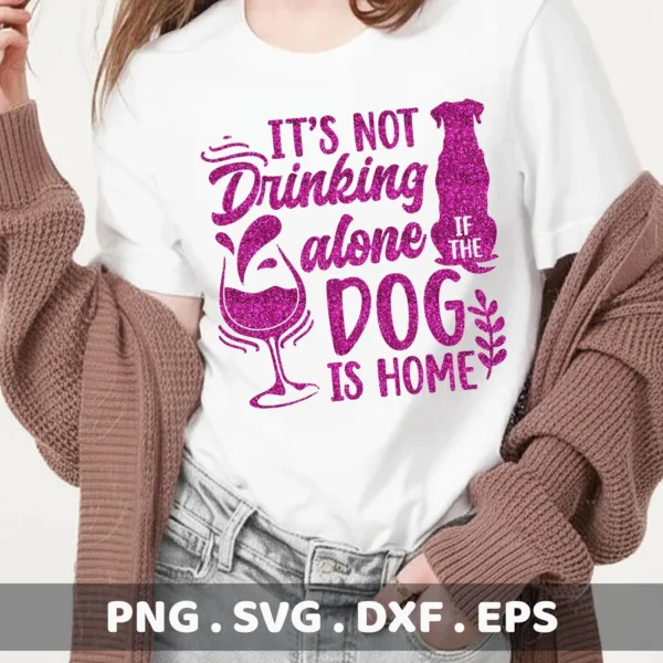 A woman wearing a white t-shirt with a glittery pink design that reads "It's not drinking alone if the dog is home," featuring a wine glass and dog silhouette, representing a digital download bundle (SVG, PNG).