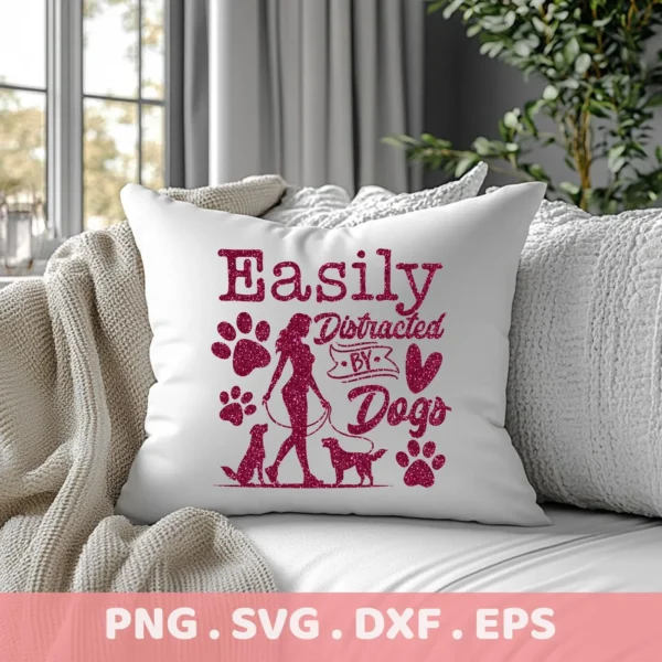 White throw pillow on a couch displaying a "Easily Distracted By Dogs" SVG Cricut Design with a woman walking two dogs, paw prints, and heart, representing a digital download bundle (SVG, PNG).