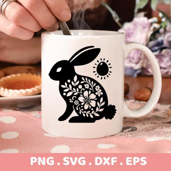 A white mug displays a black silhouette of a floral Easter bunny, representing a Floral Easter Bunny SVG File digital download bundle (SVG, PNG).