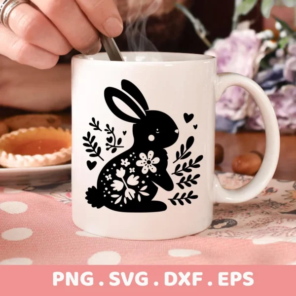 Close-up of a white mug featuring a black silhouette of a floral bunny, a Floral Bunny SVG Cricut Design, indicating a digital download bundle including SVG and PNG files.