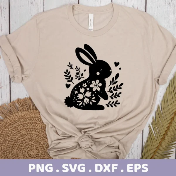 A beige t-shirt displays a black silhouette of a floral bunny, surrounded by floral elements and hearts, representing a Floral Bunny SVG Cricut Design digital download bundle (SVG, PNG).