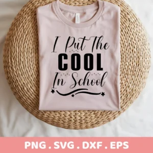 A folded light pink t-shirt with the text "I Put The COOL In School" in black lettering, displayed on a round woven mat, representing a Cool School SVG Design available as a digital download bundle (SVG, PNG).