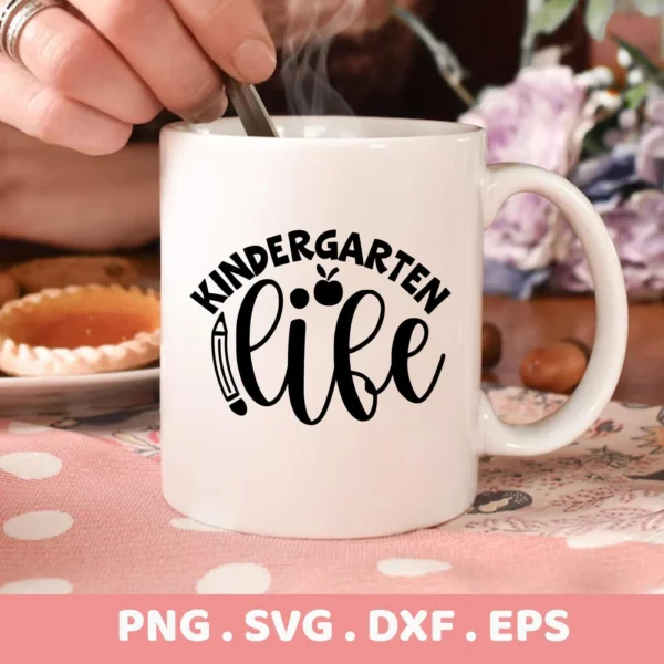 A white mug with the "Kindergarten Life SVG Design" featuring an apple and pencil graphic, presented as a digital download bundle (SVG, PNG).