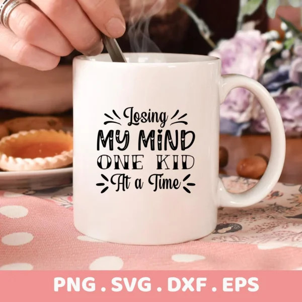 Close-up of a white mug with the text "Losing My Mind One Kid At a Time" in black lettering, part of a digital download bundle including SVG and PNG formats.