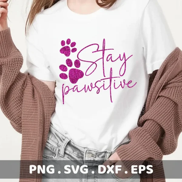 A woman wearing a white t-shirt with a pink glittery "Stay Pawsitive" design and paw prints, showcasing a digital download bundle (SVG, PNG) for Cricut and other cutting machines.